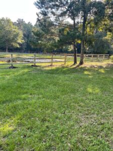 A rustic wooden split-rail fence extending across a green landscape by Stono Fencing & Exteriors in Johns Island, SC