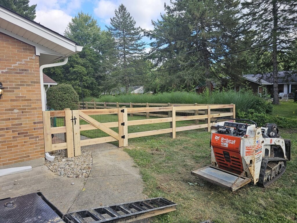 A newly installed wooden split-rail fence with wire mesh and a gate by Affordable Fence Builders in Dayton, OH.