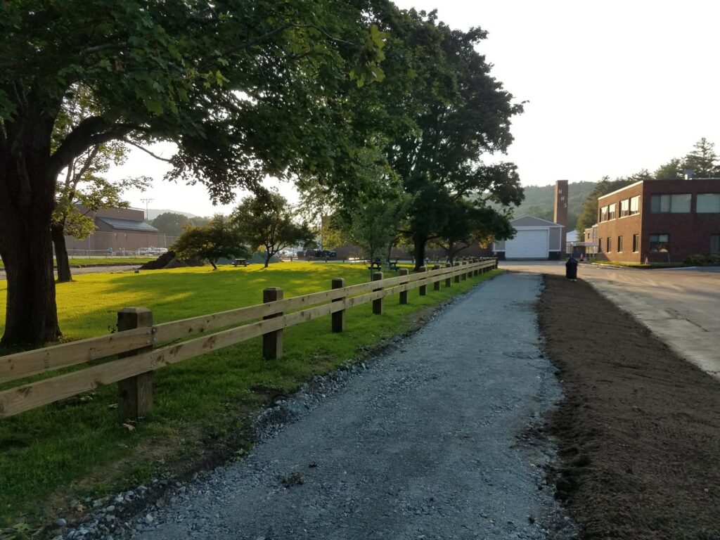A wooden split-rail fence installed along a gravel path by 802 Fence Company LLC in Shoreham, VT.