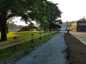 A wooden split-rail fence installed along a gravel path by 802 Fence Company LLC in Shoreham, VT.