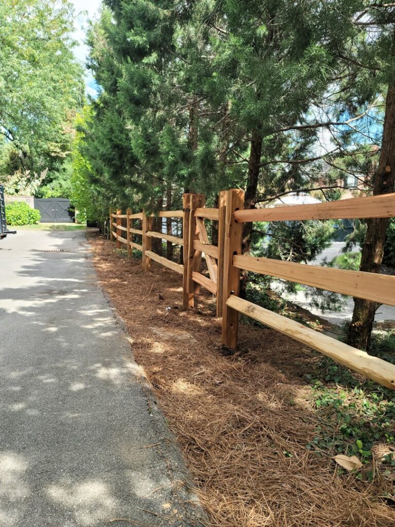 A newly installed wooden split-rail style fence along a paved path by Border Built Fencing in Florence, KY.