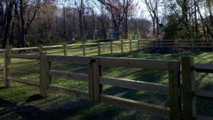A newly installed wooden split-rail fence with a gate in a residential backyard by Statewide Fencing, Inc. in Racine, WI.