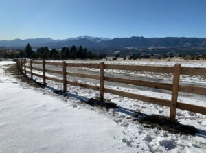 A wooden split-rail fence in a snowy landscape with mountains, installed by Colorado Springs Fence Company in Colorado Springs, CO.