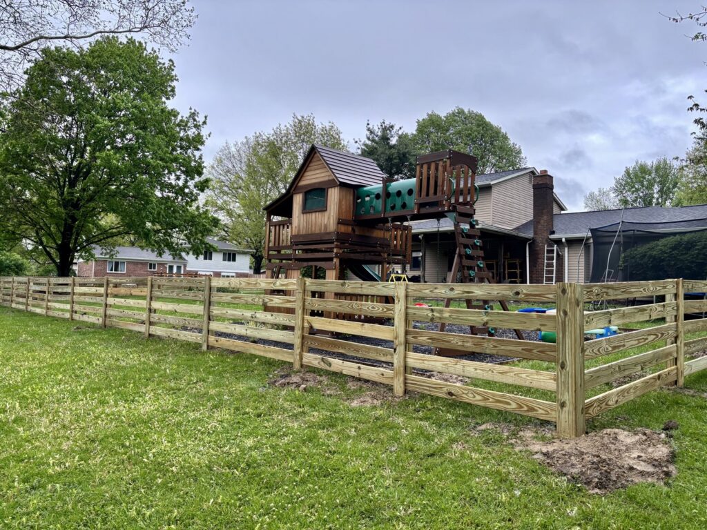 A wooden split-rail fence with wire mesh installed around a backyard playset by D&M Renovation Services LLC in Columbus, OH.