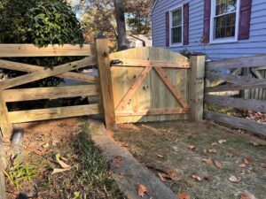 A rustic wooden split-rail style fence featuring a custom-built wooden gate, installed by AFK FENCE LLC in Waldorf, MD.