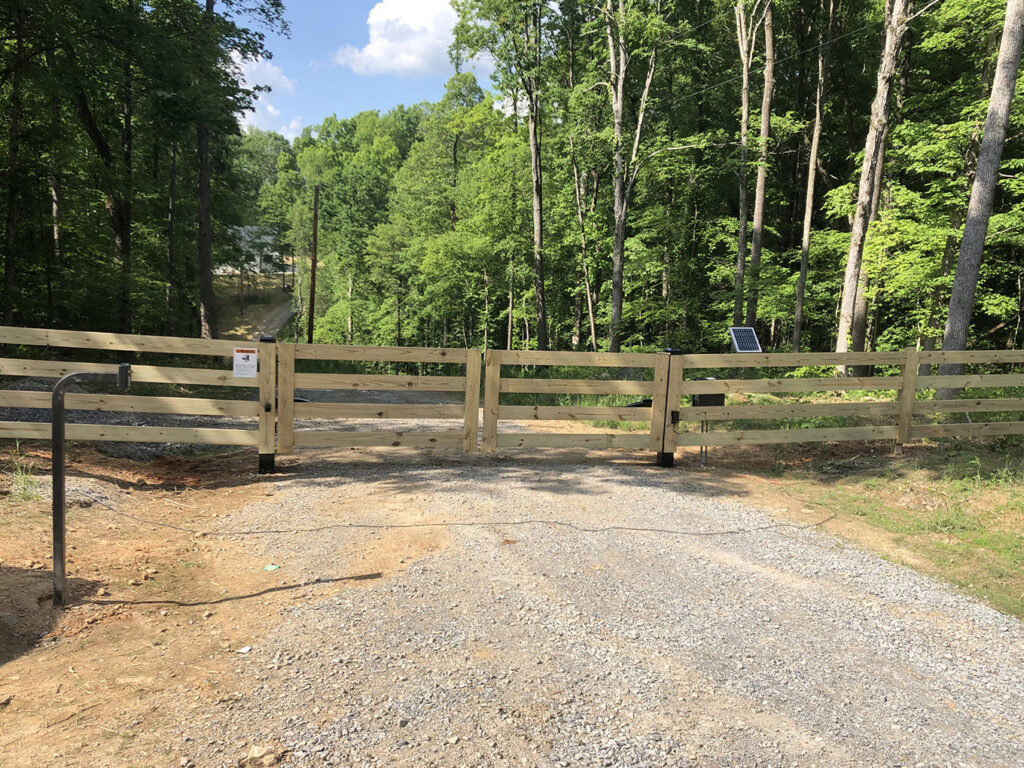 A rustic wooden split-rail fence with a gate installed along a gravel driveway by RUCO Fence in Huntsville, AL.