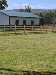 Wooden split-rail fence with wire mesh installed by National Fence and Gate in Ironton, MO, next to a building.