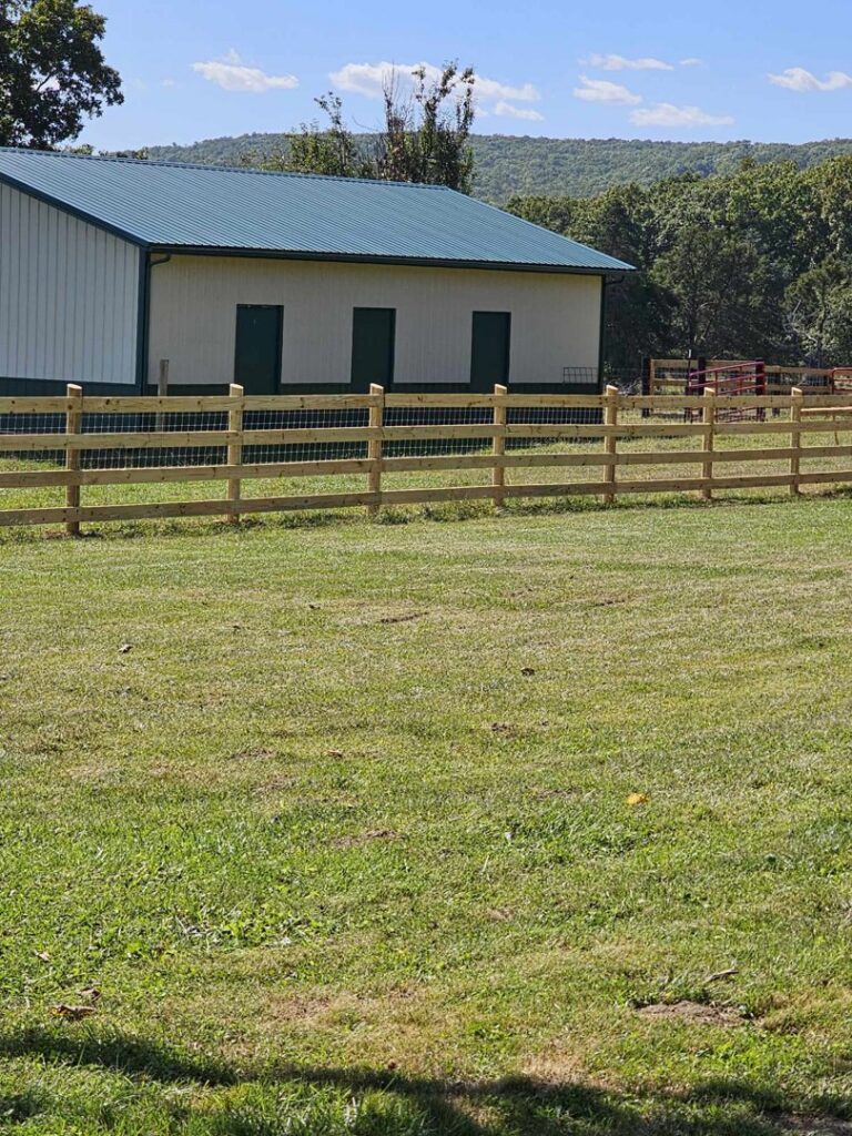 Wooden split-rail fence with wire mesh installed by National Fence and Gate in Ironton, MO, next to a building.
