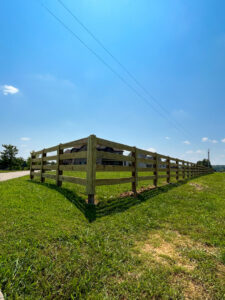 A long wooden split-rail fence with wire mesh installed along a road by Pro Fence in Decatur, AL