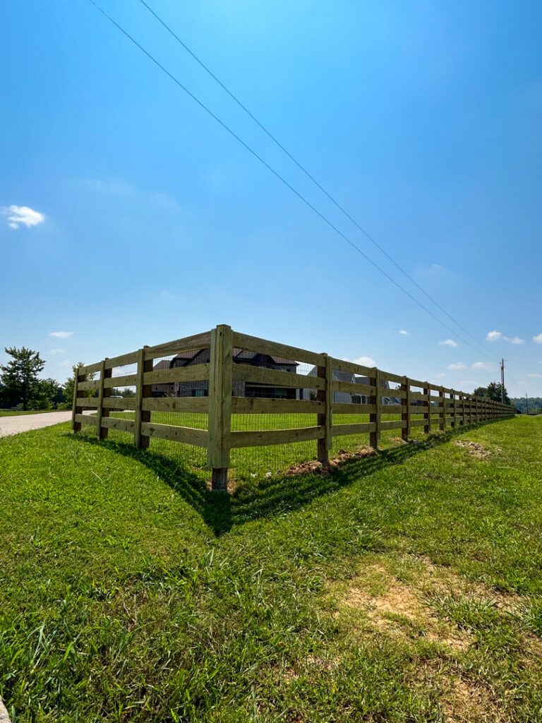 A long wooden split-rail fence with wire mesh installed along a road by Pro Fence in Decatur, AL