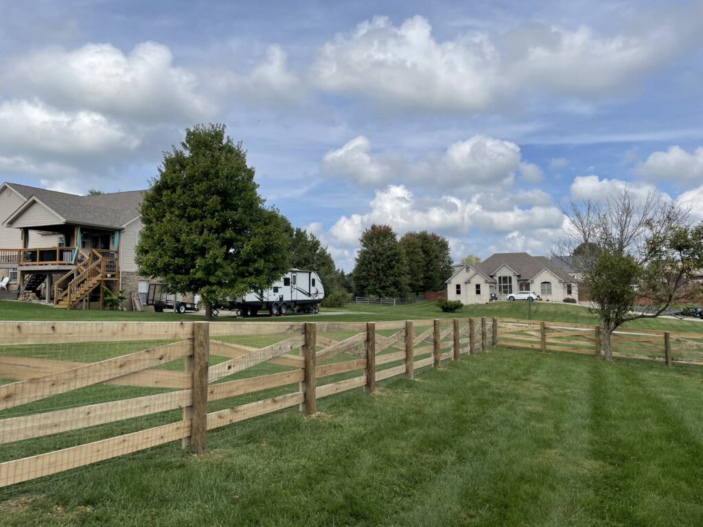 A rustic wooden split rail fence with wire mesh, providing a charming boundary for a residential property by Roark Fencing in Lexington, KY.
