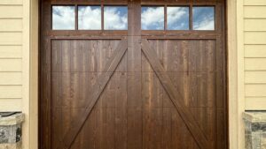 A close-up of a newly installed wooden-style garage door with top windows by Prutch's Garage Door in Colorado Springs, CO