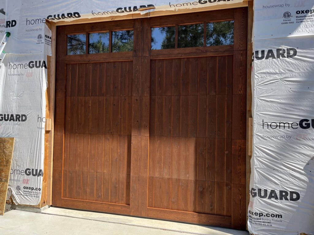 A beautiful wooden-style garage door with top windows installed on a new home by Remarkable Door Company in Spokane, WA.