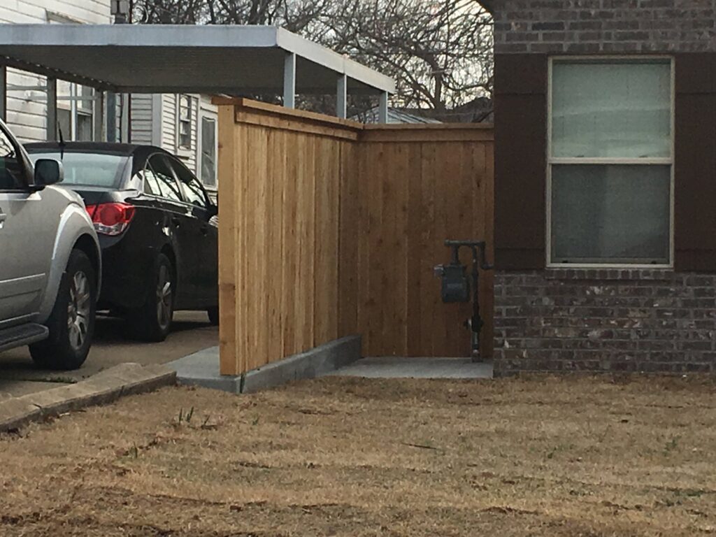 A custom wooden utility screen fence installed next to a residential home by D-Fence of Tulsa in Tulsa, OK.
