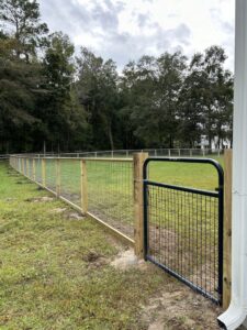 A wooden fence with wire mesh and a black metal gate for property access by Stono Fencing & Exteriors in Johns Island, SC