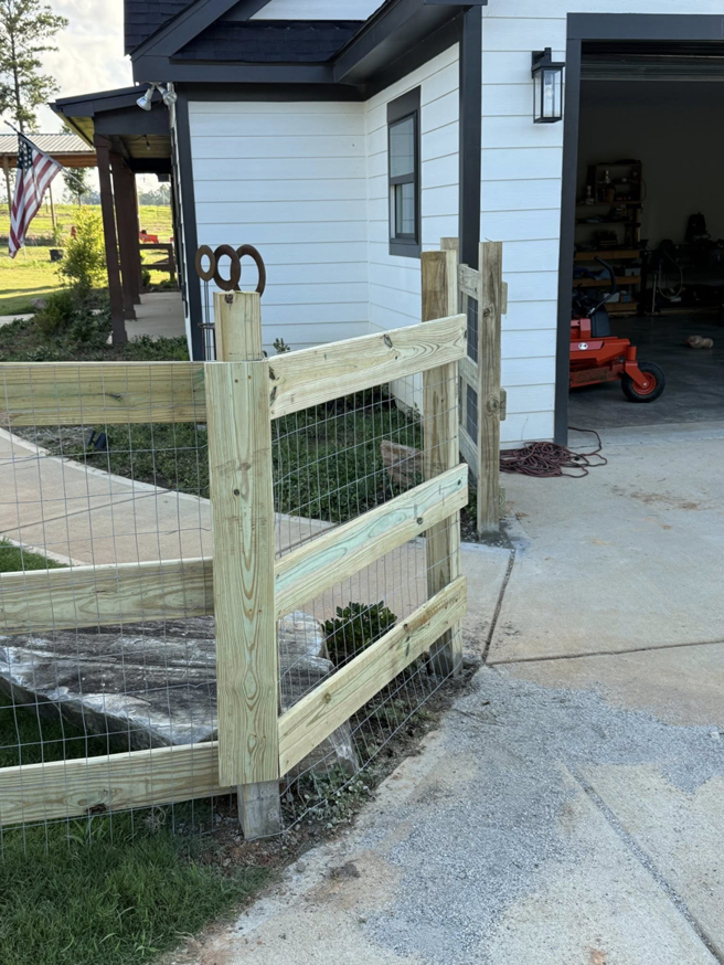 A custom wooden and wire mesh fence with a small gate installed next to a modern home by G2 Home Solutions in Phenix City, AL.
