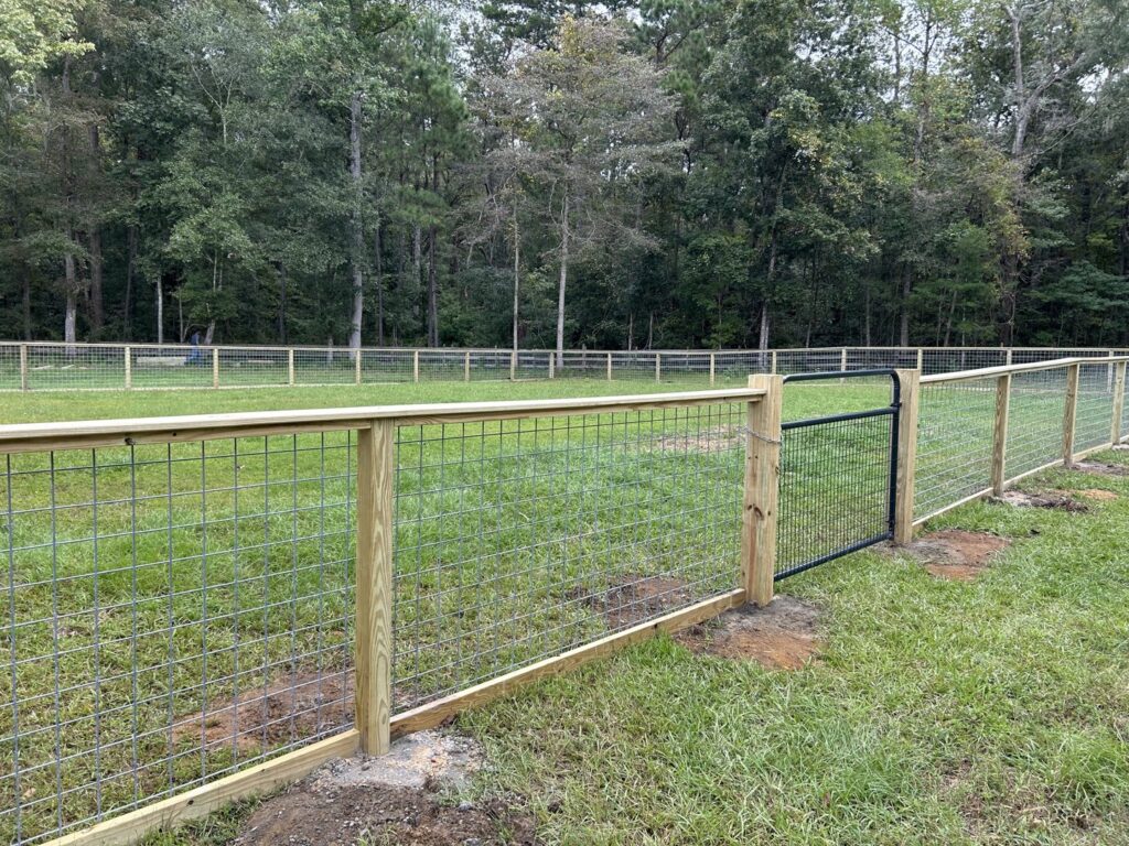 A wooden fence with wire mesh and a black metal gate installed by Stono Fencing & Exteriors in Johns Island, SC
