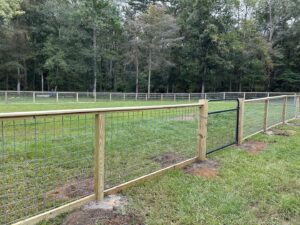 A wooden fence with wire mesh and a black metal gate installed by Stono Fencing & Exteriors in Johns Island, SC