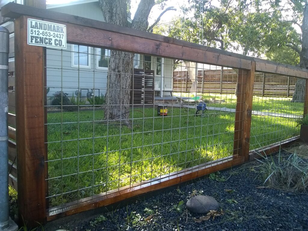 A wooden fence with wire mesh panels and a business sign by Landmark Fence & Deck Company in Saint Paul, MN.