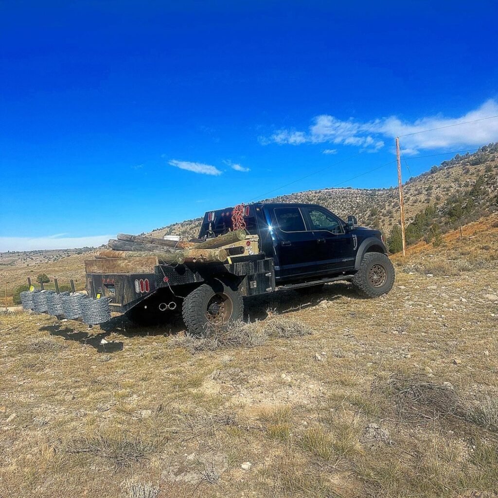 A work truck loaded with wooden fence posts and rolls of wire, ready for a fencing project by Cool Hand Fencing and Wyo War Wagons in Laramie, WY.