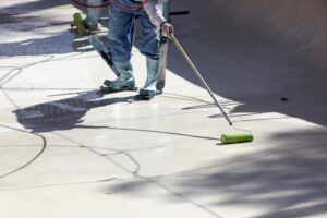 A pool contractor applying a fresh coating inside an empty pool during construction by Polar Pool and Spa in Vancouver, WA.