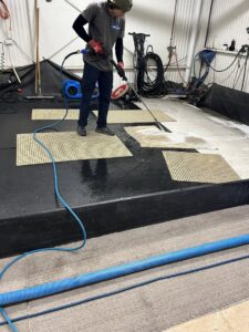 A worker from All American Carpet & Tile pressure washing area rugs as part of their cleaning service in San Diego, CA