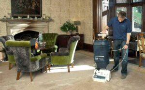 A worker cleaning a carpet in a formal room with a professional carpet cleaning machine for Ecodry Carpet Cleaning Las Vegas, NV.