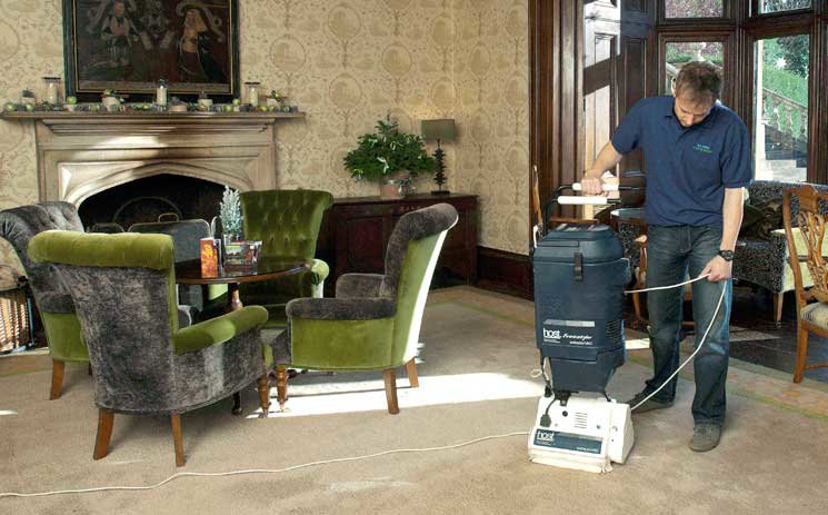 A worker cleaning a carpet in a formal room with a professional carpet cleaning machine for Ecodry Carpet Cleaning Las Vegas, NV.
