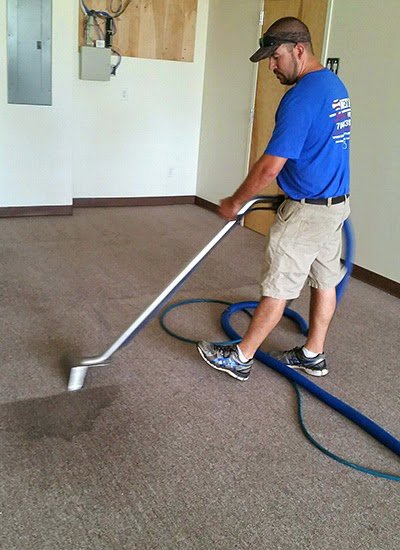 A Metro Steamway Inc. technician actively cleaning a carpet with professional equipment in Charlotte, NC.