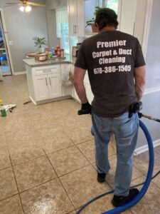 A worker cleaning a carpeted floor with a professional machine at Premier Carpet & Duct Cleaning in Athens, GA.