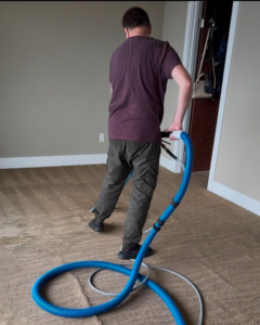 A worker actively cleaning a carpet with a professional cleaning wand by Alex & Mary Carpet & Upholstery Cleaning in Tacoma, WA.