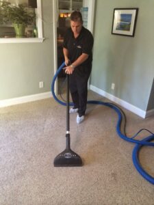 A professional worker from Encore Carpet Care cleaning a residential carpet with a specialized wand in Fort Wayne, IN.