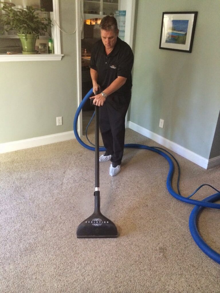 A professional worker from Encore Carpet Care cleaning a residential carpet with a specialized wand in Fort Wayne, IN.