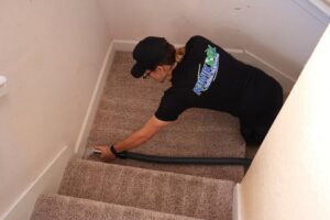 A worker from Rhode Island Kwik Dry cleaning carpeted stairs with a specialized tool in Providence, RI.