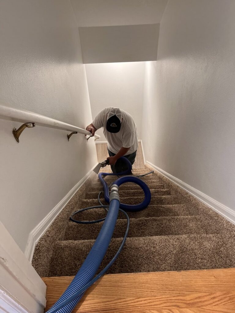 A worker professionally cleaning carpeted stairs with a wand by Tailor Maid Carpet Cleaning in Colorado Springs, CO.