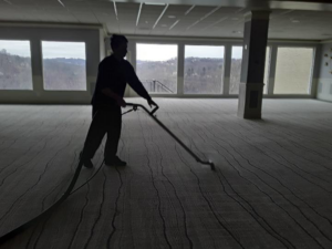 A worker cleaning a large commercial carpet with professional equipment at Rowland Brothers Carpet Cleaning Service in Morgantown, WV