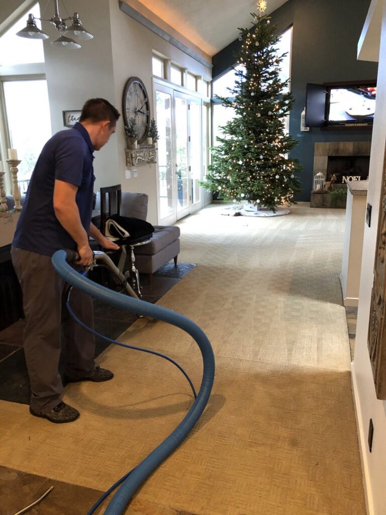 A worker professionally cleaning a living room carpet with a machine for Spectrum Cleaning & Restoration in Medford, OR