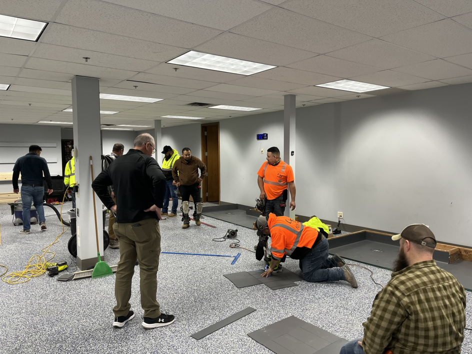A professional worker kneeling and precisely cutting flooring tiles during an installation by Hank's Specialties, Inc. in Saint Paul, MN.