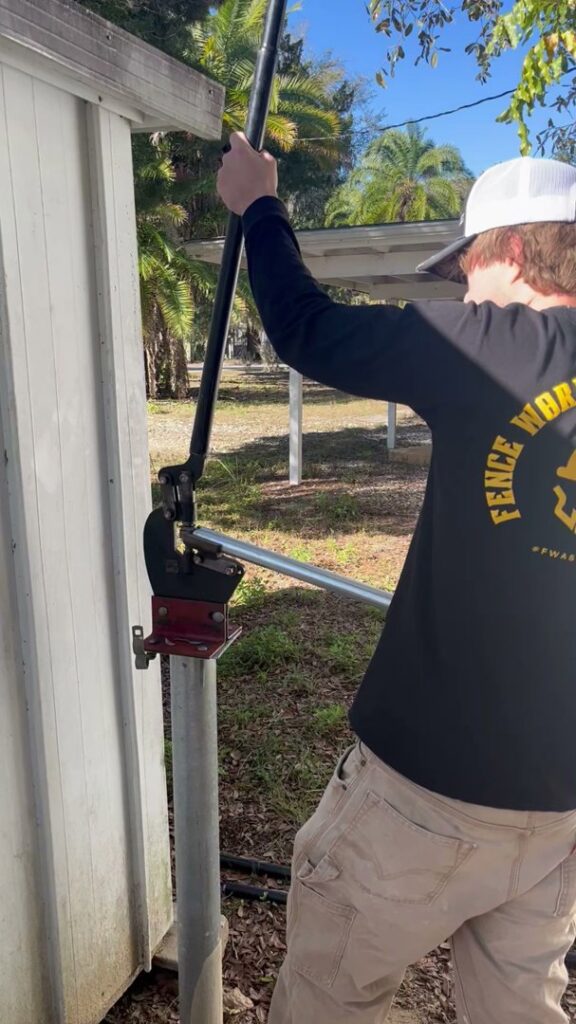 A worker cutting a metal fence post with a specialized tool for Aarons fence in Homosassa Springs, FL