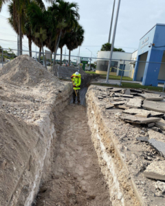 A worker digging a trench for electrical conduit installation by Canseco Electrical Contractors, Inc. in Miami, FL.