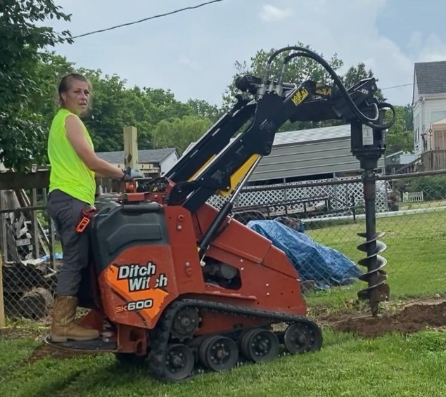 A worker operating a Ditch Witch SK600 mini skid steer to dig fence post holes for Stapleton Fencing LLC in Lexington, KY.