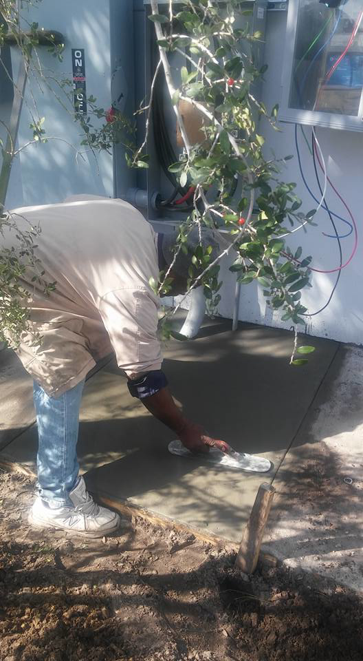 A worker finishing concrete near an outdoor electrical panel for Electrical Partners of Central Florida in Altamonte Springs, FL