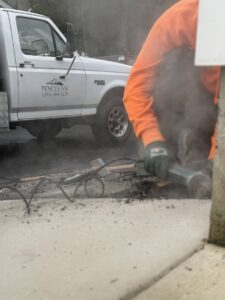 A Fences NW LLC worker grinding concrete on a job site in Spanaway, WA, with a company truck nearby