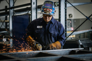 A worker grinding metal with sparks flying in the fabrication shop at Hirschi Iron in North Las Vegas, NV.