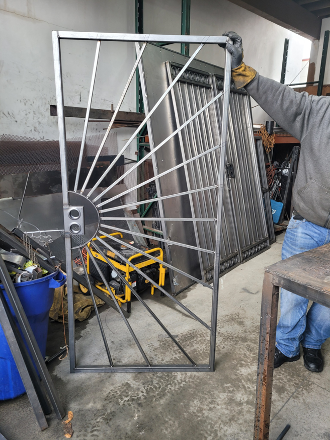 A worker holding a custom-designed iron gate frame in the workshop at HBHB Iron Works in Los Angeles, CA.