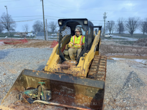 A worker in a skid steer loader performing ground work for a geothermal system installation by Jackson Geothermal in Mansfield, OH.