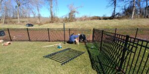 A worker installing a black metal fence in a residential area for Universal Fence LLC in Drainesville, VA.