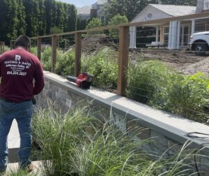 A worker installing a cable railing system on a retaining wall for RP Fencing & Gates in Brewster, NY