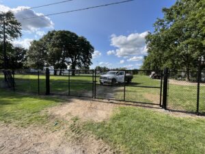 A worker installing a chain-link fence gate for Pro-Soil Site Services, Inc in Lansing, MI