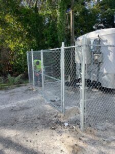 A worker installing a new chain-link fence for a commercial property by Julien Affordable Fencing LLC in Jacksonville, FL
